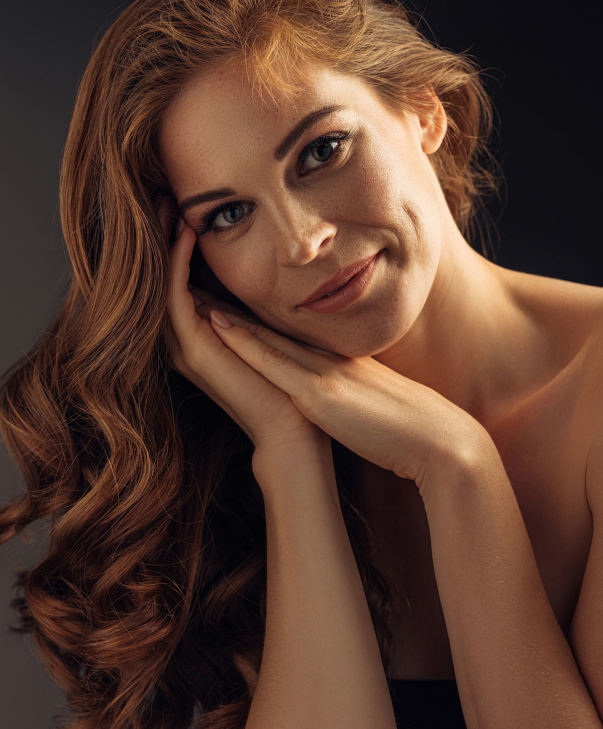 Woman with wavy hair, smiling thoughtfully.