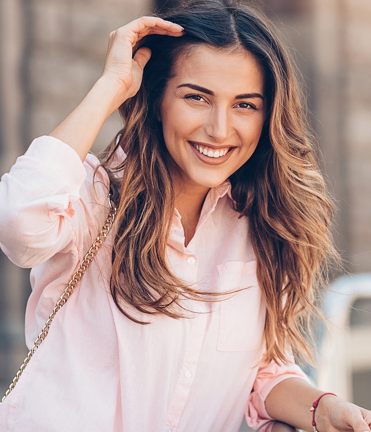Smiling woman with long hair and pink shirt.