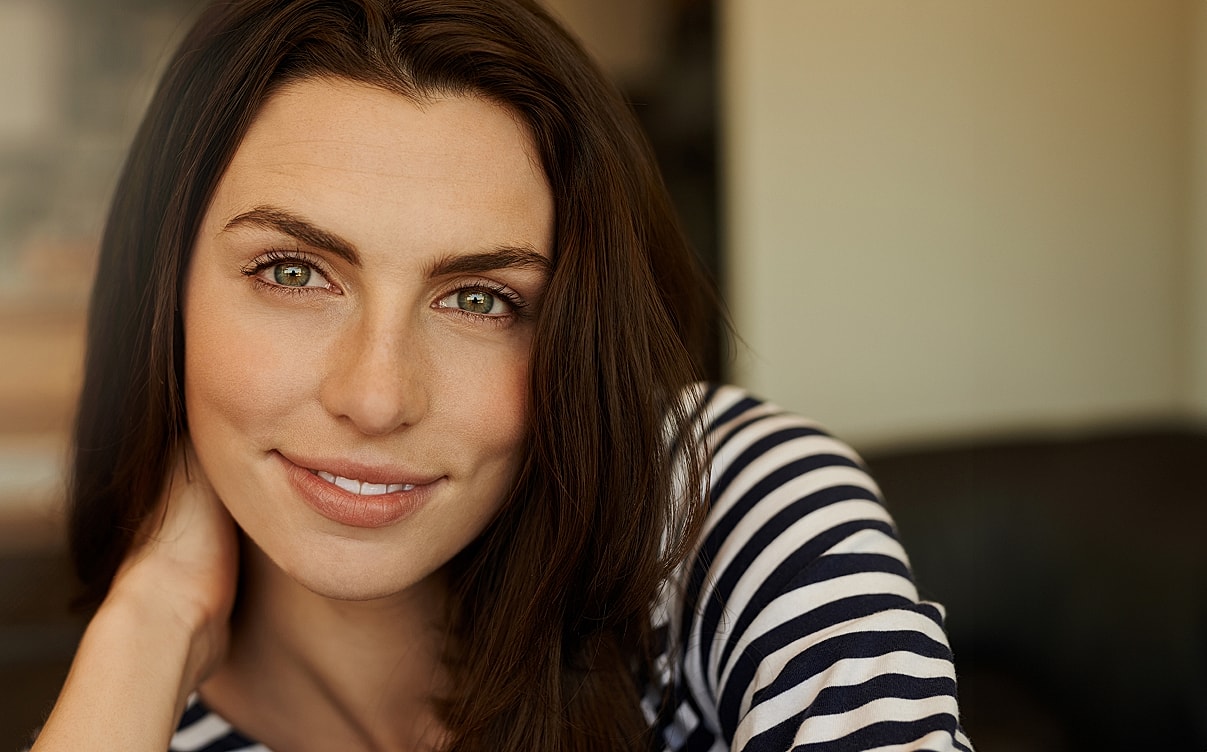 Smiling woman with long dark hair indoors.