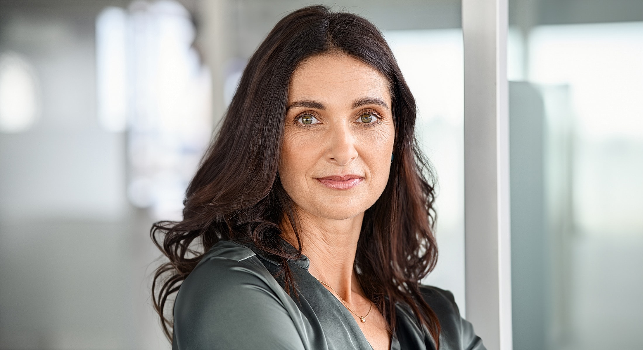 Woman with long hair, looking confidently at camera.