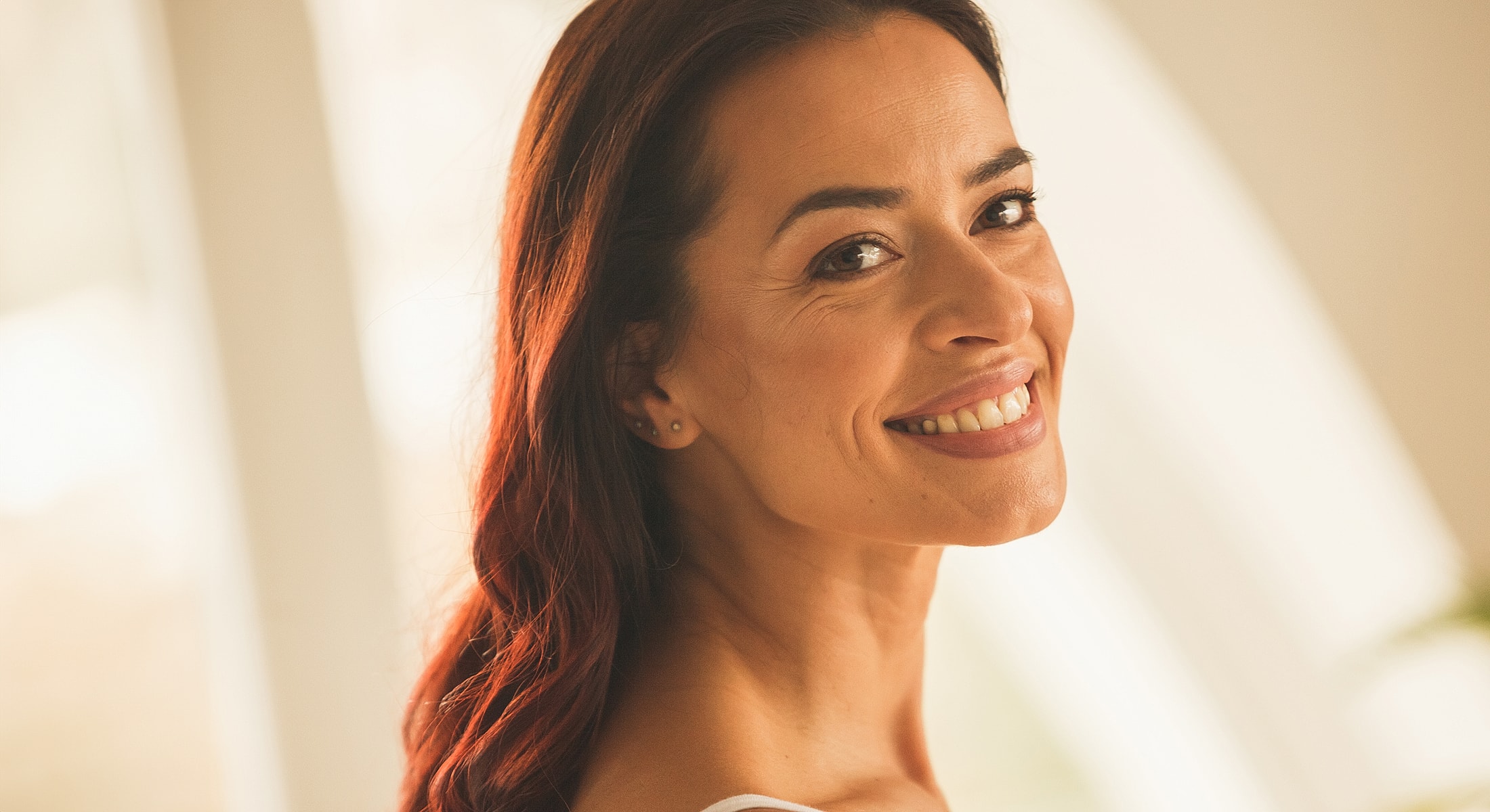 Smiling woman with long, dark hair indoors.