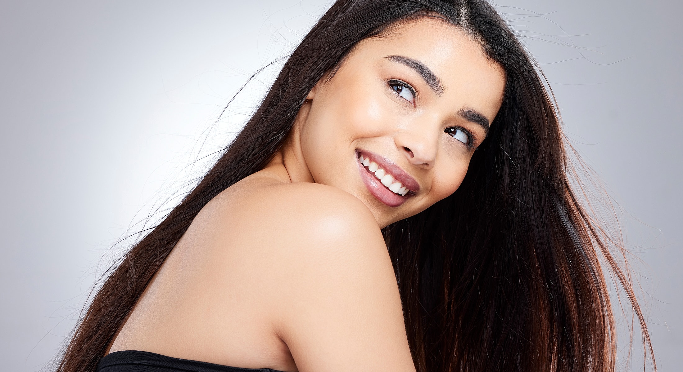 Smiling woman with long hair in studio lighting.